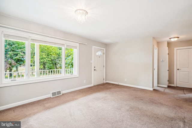 carpeted empty room featuring a notable chandelier