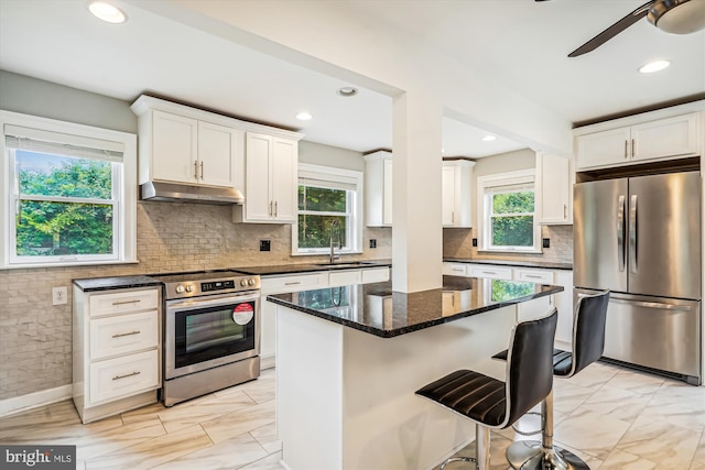 kitchen featuring a center island, sink, dark stone countertops, white cabinets, and appliances with stainless steel finishes