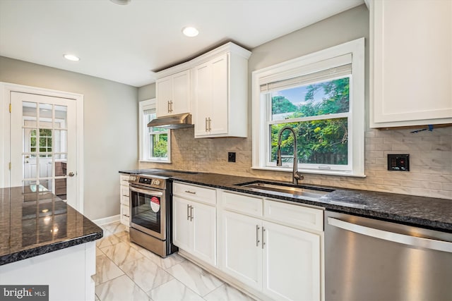 kitchen with appliances with stainless steel finishes, white cabinetry, dark stone counters, and sink