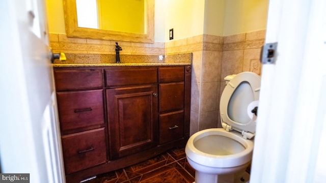 bathroom featuring vanity, toilet, and tile walls