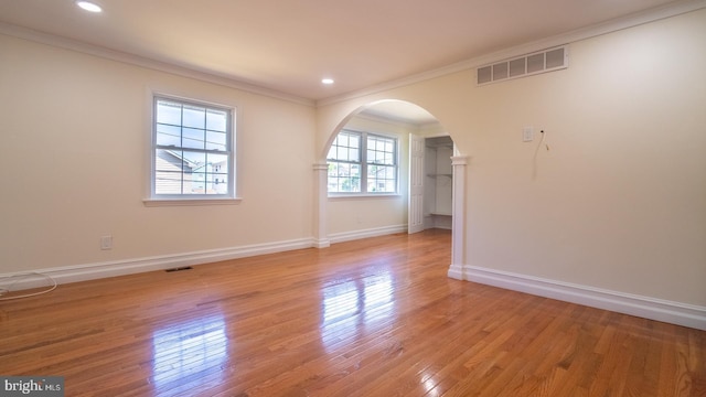 empty room with light wood-type flooring and crown molding