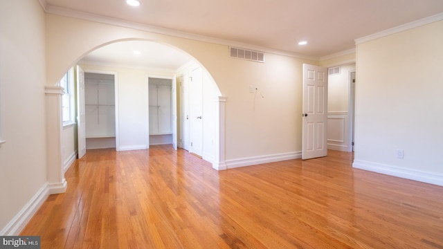 spare room with crown molding and light wood-type flooring