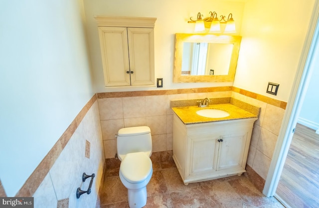 bathroom featuring vanity, toilet, and tile walls