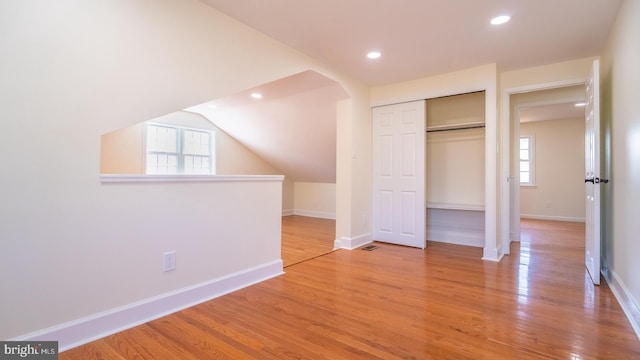 unfurnished bedroom with light hardwood / wood-style floors, vaulted ceiling, and multiple windows