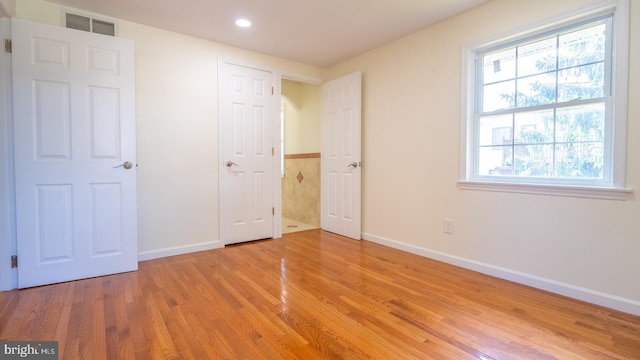 unfurnished bedroom with wood-type flooring and multiple windows