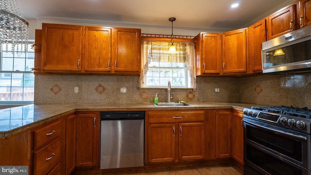 kitchen with backsplash, sink, stainless steel appliances, and hanging light fixtures