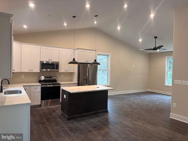 kitchen with stainless steel appliances, ceiling fan, sink, decorative light fixtures, and a center island