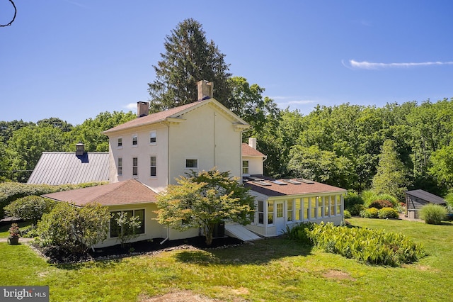 back of property with a lawn and a sunroom