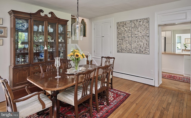 dining space with light hardwood / wood-style flooring and a baseboard radiator