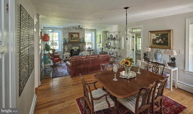 dining space featuring baseboard heating, a wood stove, and hardwood / wood-style floors