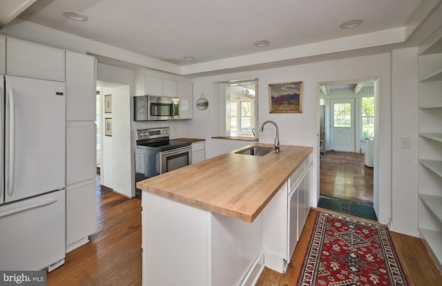 kitchen featuring appliances with stainless steel finishes, a healthy amount of sunlight, sink, a center island with sink, and white cabinetry