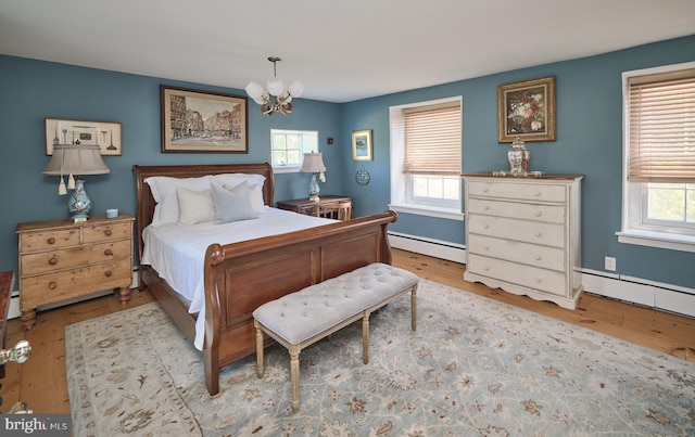 bedroom with light wood-type flooring, baseboard heating, and an inviting chandelier