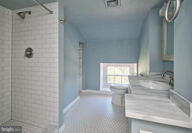 bathroom with vanity, toilet, a tile shower, and built in features