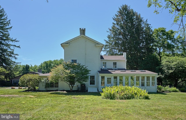 rear view of property with a sunroom and a yard