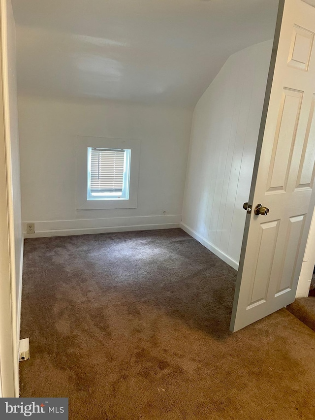 carpeted spare room featuring lofted ceiling