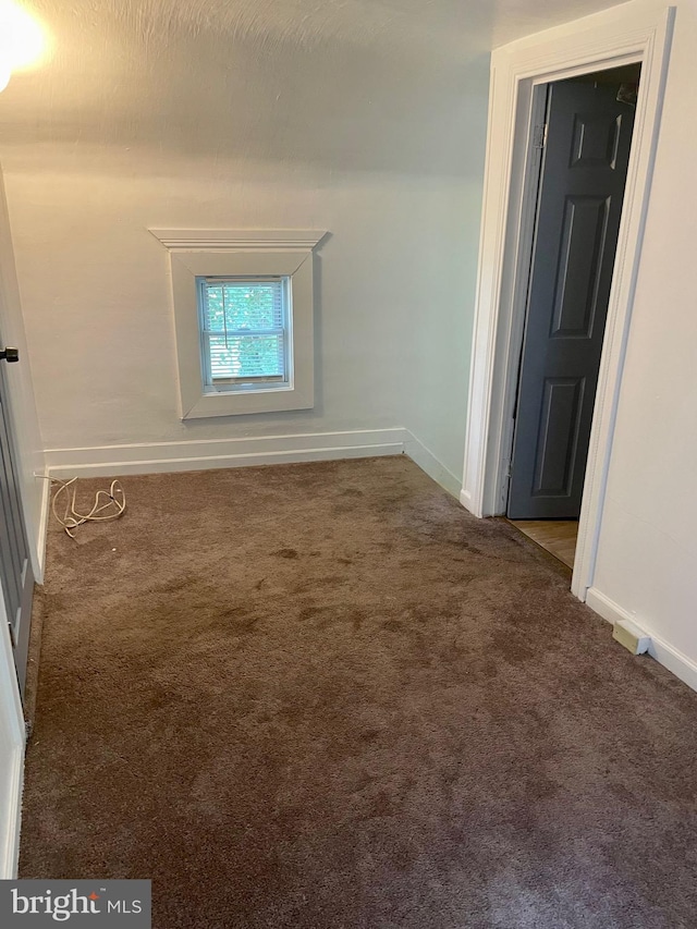 unfurnished room featuring dark colored carpet