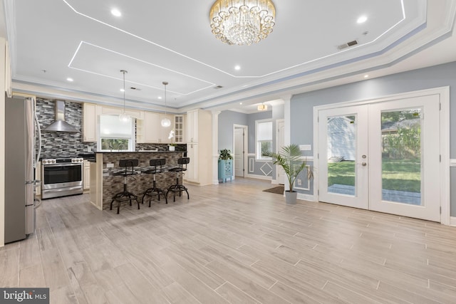 dining space featuring a chandelier, french doors, light hardwood / wood-style floors, and a tray ceiling