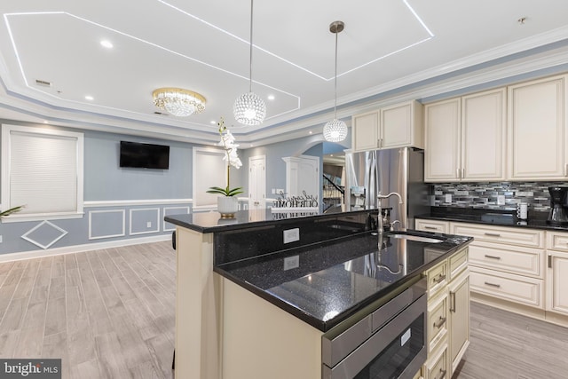 kitchen with cream cabinetry, pendant lighting, a center island with sink, and built in microwave