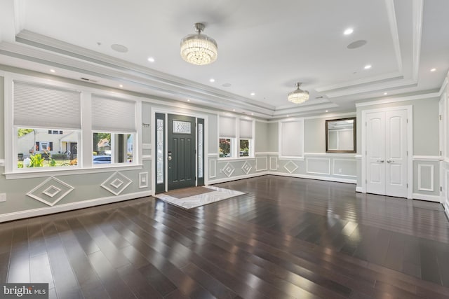 unfurnished living room with a healthy amount of sunlight, an inviting chandelier, wood finished floors, and a decorative wall