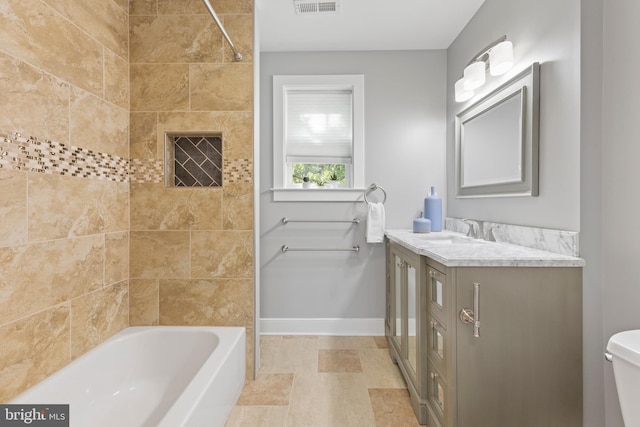 full bathroom with tiled shower / bath, vanity, and toilet