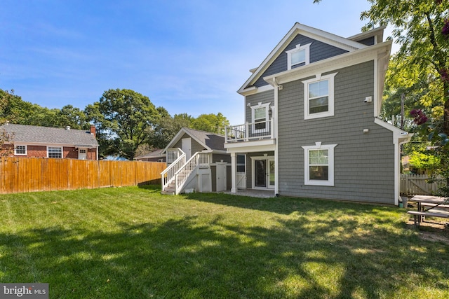 back of house featuring a yard and a balcony