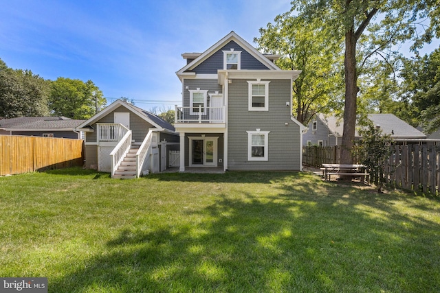 back of property with a yard, a balcony, and french doors