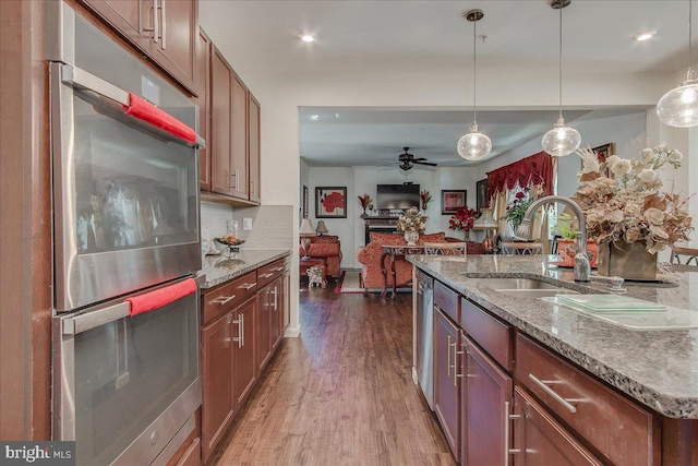 kitchen featuring ceiling fan, sink, hanging light fixtures, stainless steel appliances, and dark hardwood / wood-style floors