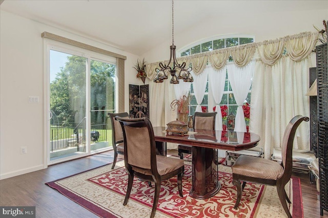 dining room featuring wood-type flooring, lofted ceiling, an inviting chandelier, and a healthy amount of sunlight