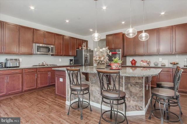 kitchen featuring pendant lighting, light wood-type flooring, stainless steel appliances, and a kitchen island