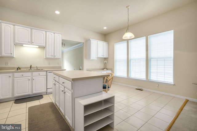 kitchen featuring a sink, white cabinets, light countertops, a center island, and pendant lighting