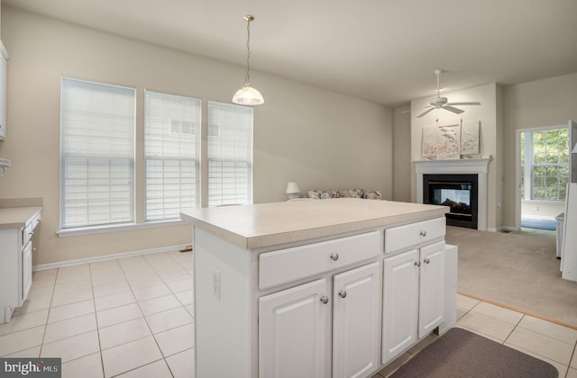 kitchen featuring open floor plan, a center island, decorative light fixtures, light countertops, and white cabinetry