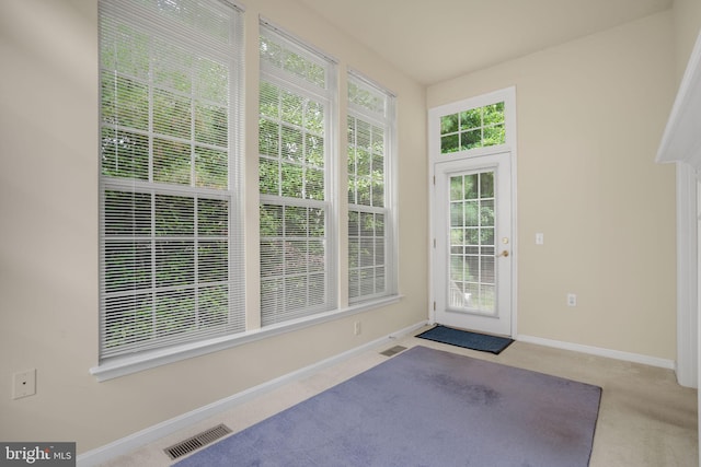 doorway with baseboards, visible vents, and light colored carpet