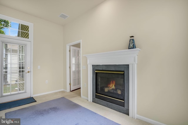 unfurnished living room with visible vents, baseboards, light colored carpet, and a high end fireplace