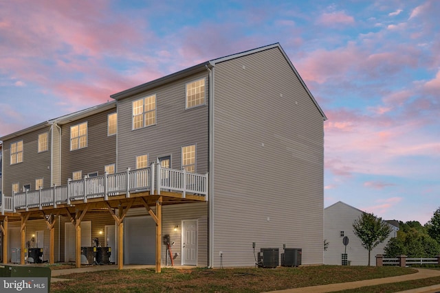 back house at dusk with a deck and central air condition unit