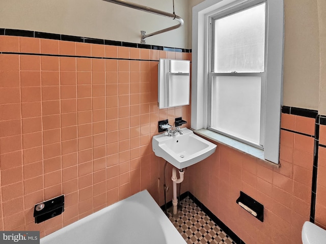 full bathroom featuring a sink, tile walls, and wainscoting