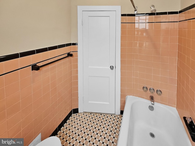 bathroom with tile walls, a bath, and walk in shower