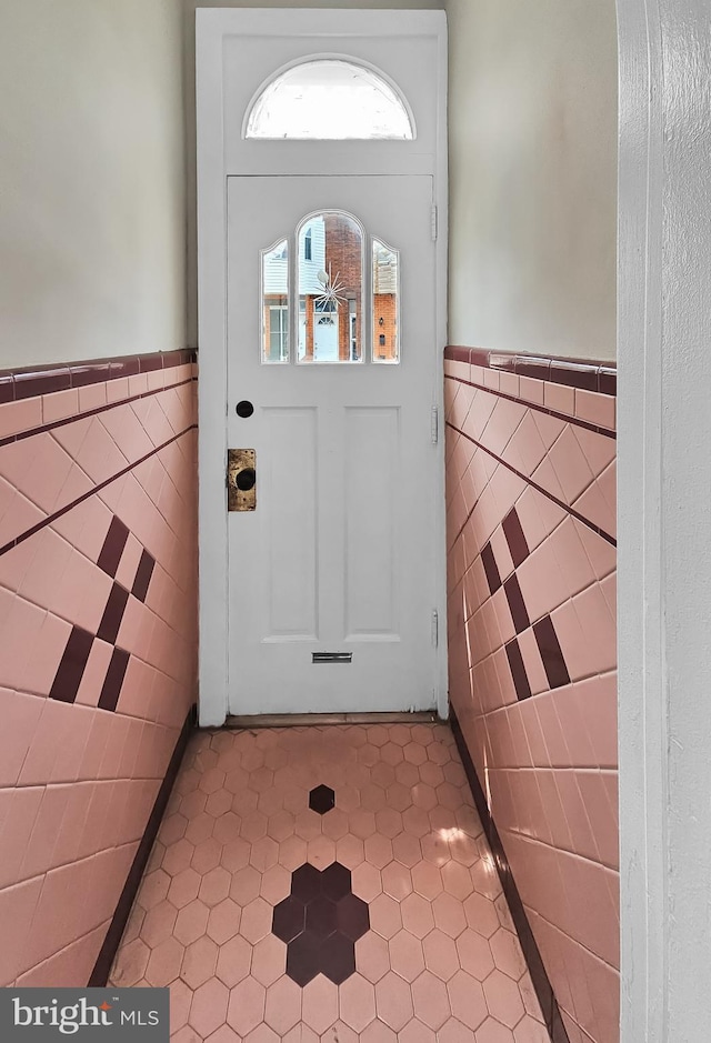 doorway to outside with tile patterned floors and tile walls