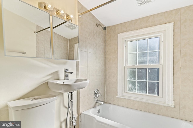 full bathroom with tiled shower / bath, sink, and toilet