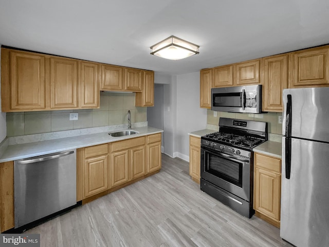 kitchen featuring tasteful backsplash, appliances with stainless steel finishes, sink, and light hardwood / wood-style flooring