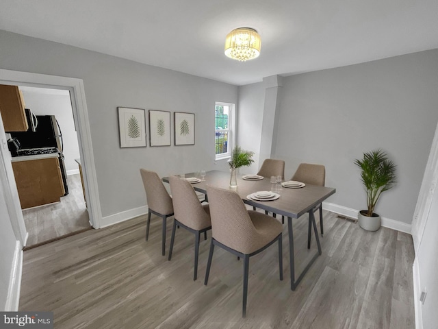 dining space featuring a notable chandelier and light wood-type flooring