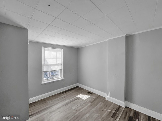 spare room with crown molding and wood-type flooring