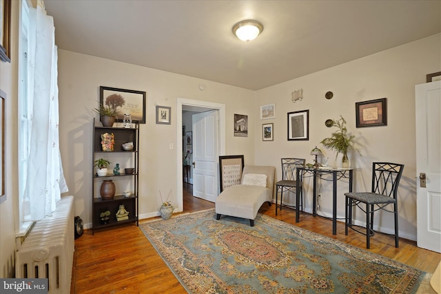 living area with hardwood / wood-style flooring and radiator