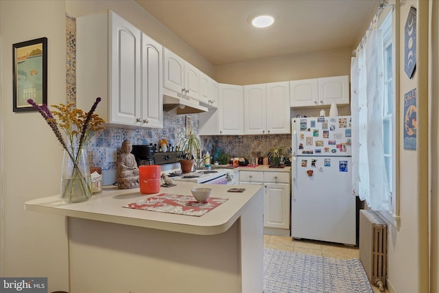 kitchen with radiator, white cabinets, white refrigerator, kitchen peninsula, and range