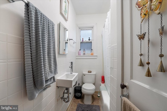 bathroom featuring toilet, tile walls, and sink