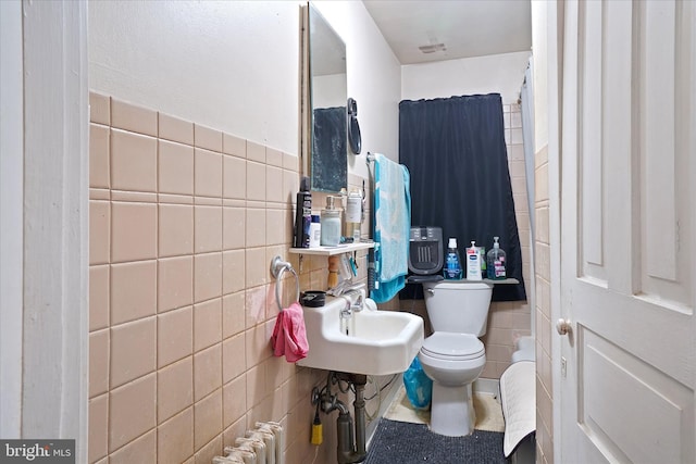 bathroom featuring radiator, toilet, tile walls, and sink