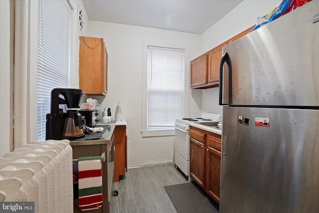 kitchen with electric stove, stainless steel refrigerator, and light hardwood / wood-style flooring