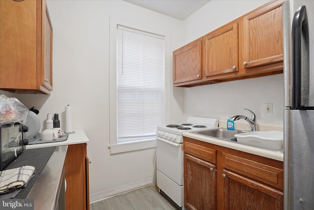 kitchen with sink, light hardwood / wood-style floors, stainless steel refrigerator, and electric stove