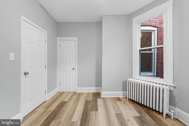 spare room with light hardwood / wood-style floors and radiator heating unit