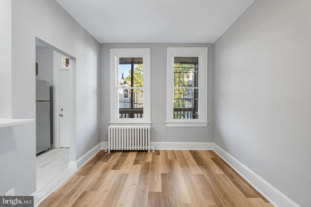 spare room featuring radiator heating unit and light hardwood / wood-style flooring