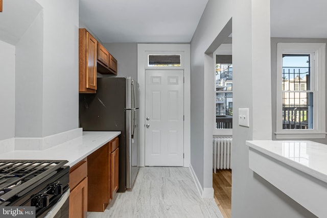 kitchen with stainless steel fridge, radiator heating unit, and black range